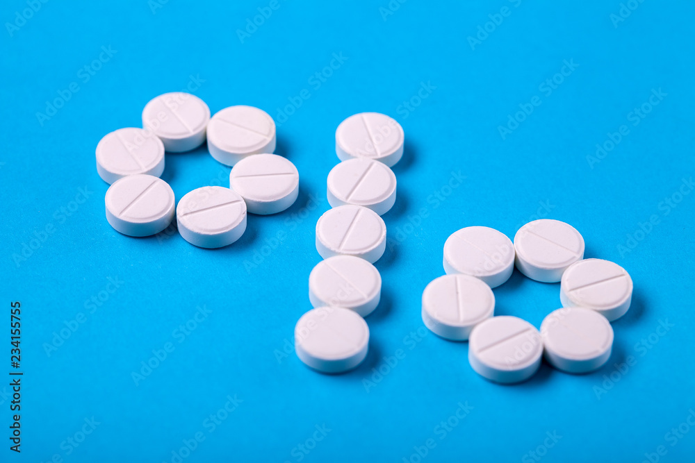 Symbol percent laid out from white round pills on blue background, close-up designation of discounts and sales. Symbol percent laid out from white round pills on blue background, close-up designation of discounts and sales.