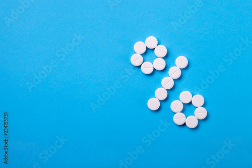 A percent sign of pills on a blue background top view with copy space for text, a conceptual background on a medical theme and a depiction of percentages for sales or indication of dosages.