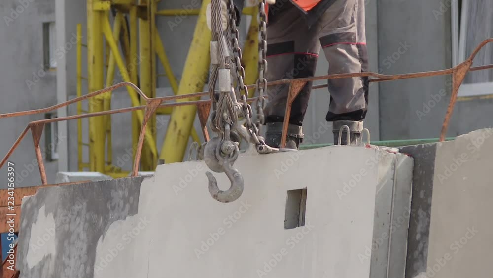 Construction site, crane lifting wall panel. Unfinished highrise