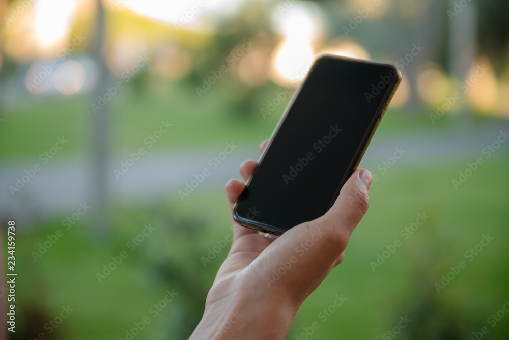 Closeup of female hands holding smart phone on outdoors background. Top side overhead view of mockup display nature backdrop, modern digital device mobil communication technology connection. Closeup of female hands holding smart phone on outdoors background. Top side overhead view of mockup display nature backdrop, modern digital device mobil communication technology connection.