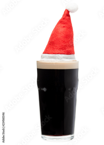 Dark ale beer in pint glass with red christmas santa hat on white background