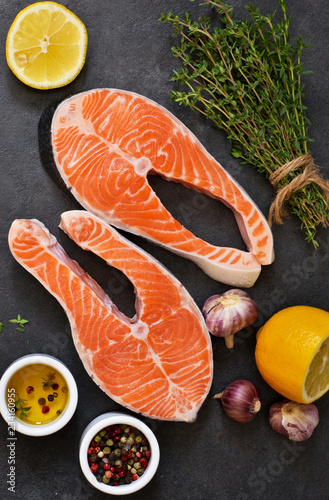 Raw salmon fish with spices on black. Top view.