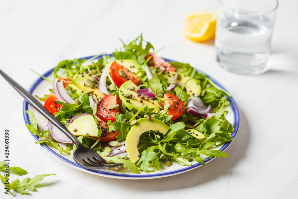 Healthy arugula, avocado, tomatoes salad on white marble background. Healthy arugula, avocado, tomatoes salad on white marble background.