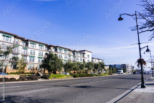 Light traffic on a street in Santa Clara on a sunny day  multifamily housing development on the side of the road  San Francisco bay area  California
