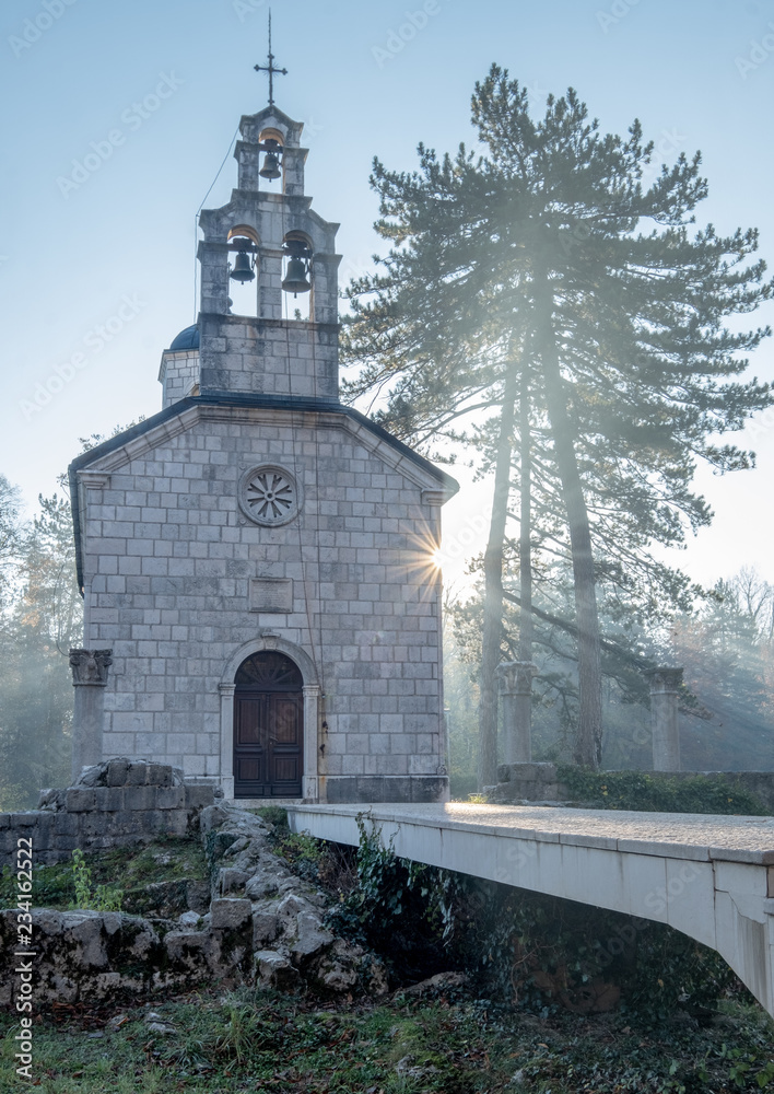 Christian Orthodox church on a clear brisk fall morning, with ray of sun beaming towards the church and tree, and a sun burst on the side in a concept of spirituality .