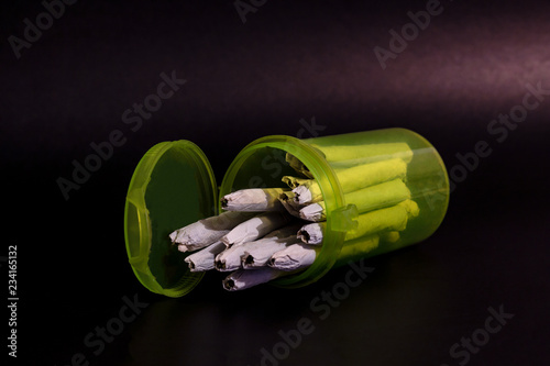 Obraz na płótnie A bright transparent green RX pill bottle filled with marijuana joints laying on its side open. w salonie