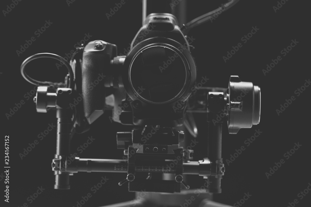 System stabilization video camera and lens on steady equipment support such as gimbal steady or stabilized. Black background