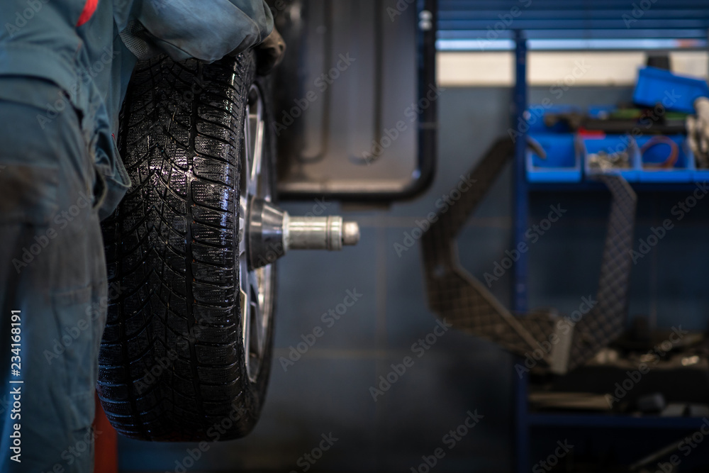 Fototapeta premium Mechanic changing a wheel of a modern car (color toned image)