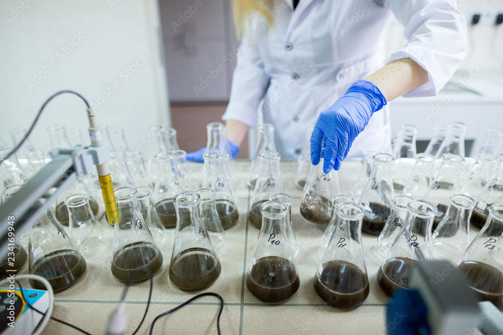 Hands of the scientist in laboratory shake a glass flasks with ...