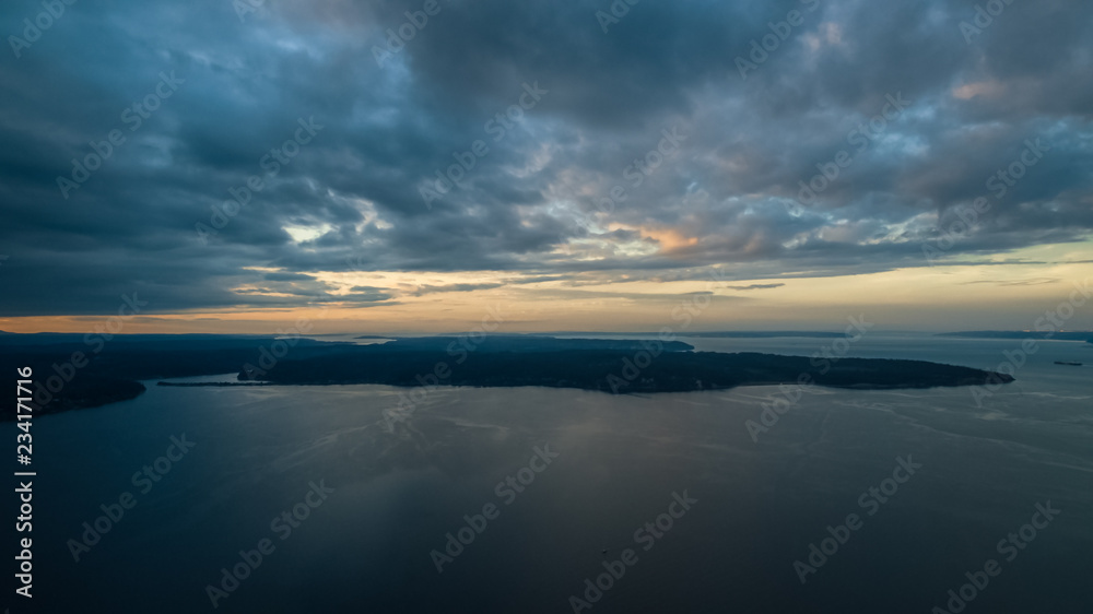 A colorful high aerial view of sunset over a Pacific Northwest island with dynamic clouds