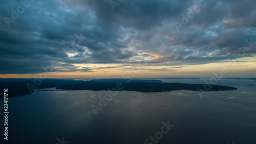 A colorful high aerial view of sunset over a Pacific Northwest island with dynamic clouds