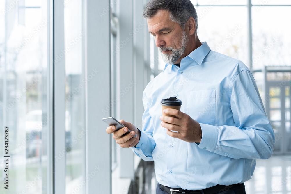 Mature business man in formal clothing using mobile phone. Serious  businessman using smartphone at work. Manager in suit using cellphone in a  modern office. Stock Photo | Adobe Stock
