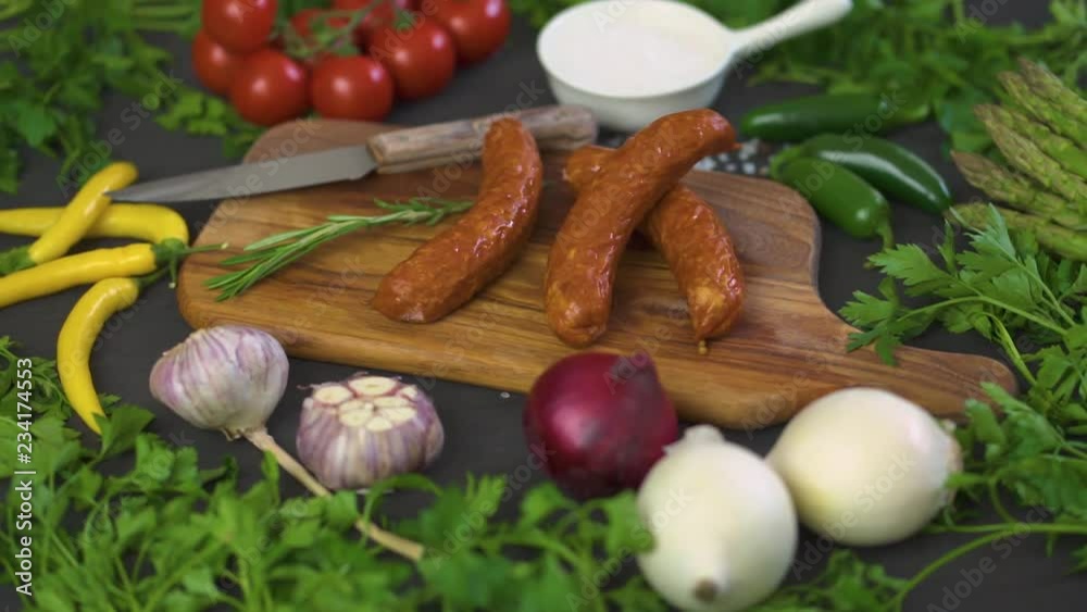 three delicious sausages with different vegetables on a wooden board, knife on a black table three delicious sausages with different vegetables on a wooden board, knife on a black table