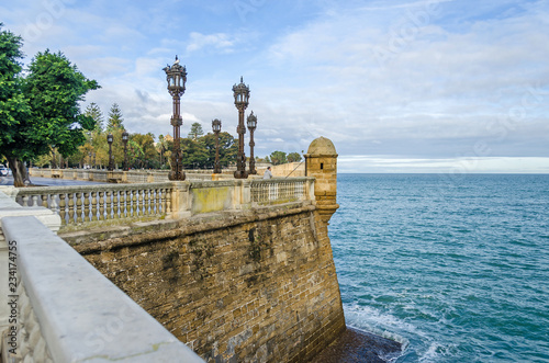 City walls with the park of Alameda Apodaca and a man fishing in the Old Town of Cadiz, Spain photo