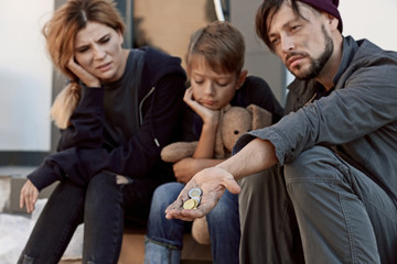 Poor homeless family begging on city street