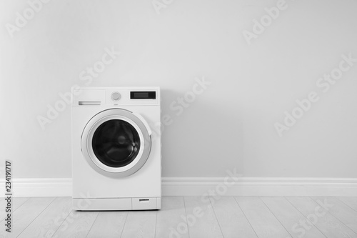 Washing machine near white wall, space for text. Laundry day photo