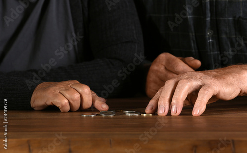 Poor elderly couple counting coins at table, focus on hands