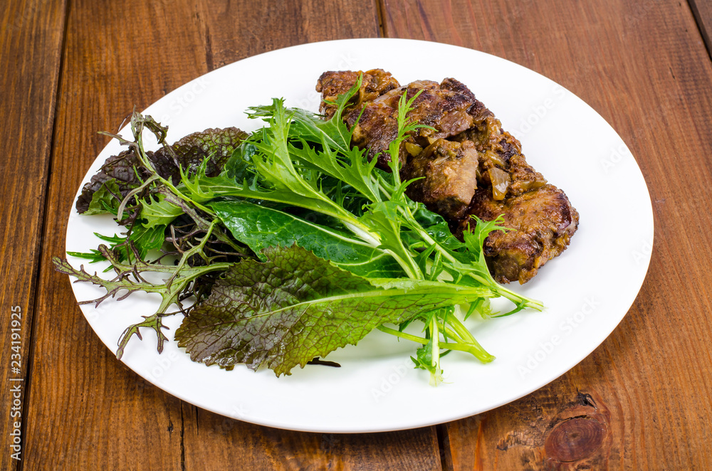 Slices of fried liver, green leaves of salads Slices of fried liver, green leaves of salads