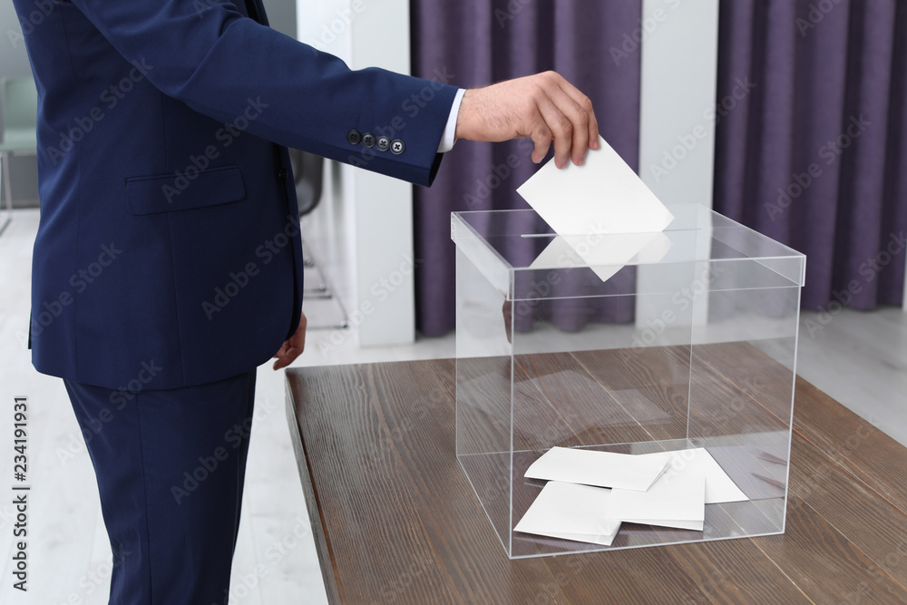 Φωτογραφία Man putting his vote into ballot box at polling station, closeup