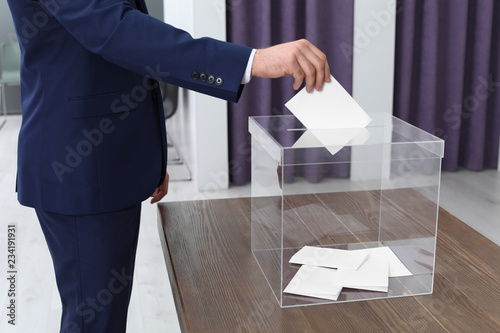 Konstfotografi Man putting his vote into ballot box at polling station, closeup