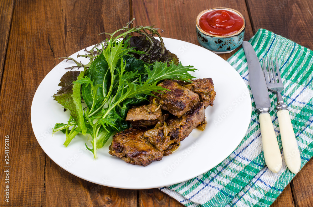 Slices of fried liver, green leaves of salads Slices of fried liver, green leaves of salads