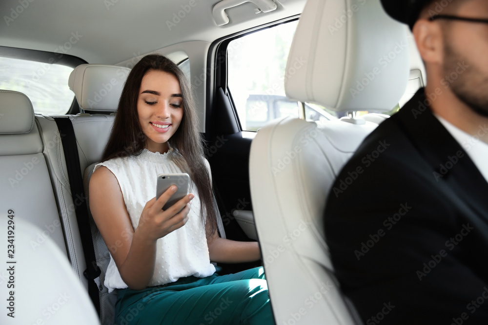 Young businesswoman with driver in luxury car. Chauffeur service