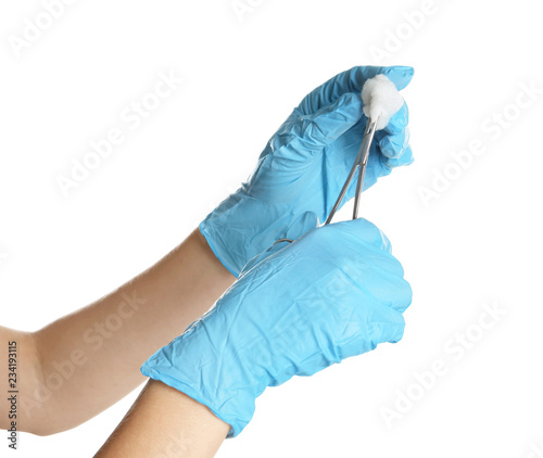 Doctor in sterile gloves holding medical clamp on white background