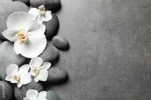Fototapeta Naklejka Na Ścianę i Meble -  Flat lay composition with spa stones and orchid flowers on grey background. Space for text