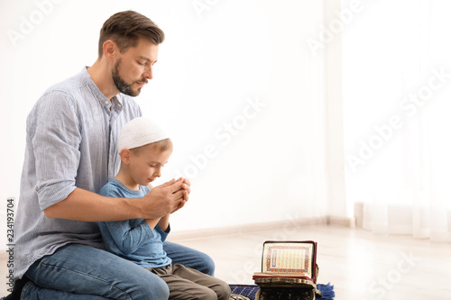 Canvas Print Muslim man and his son praying together indoors. Space for text