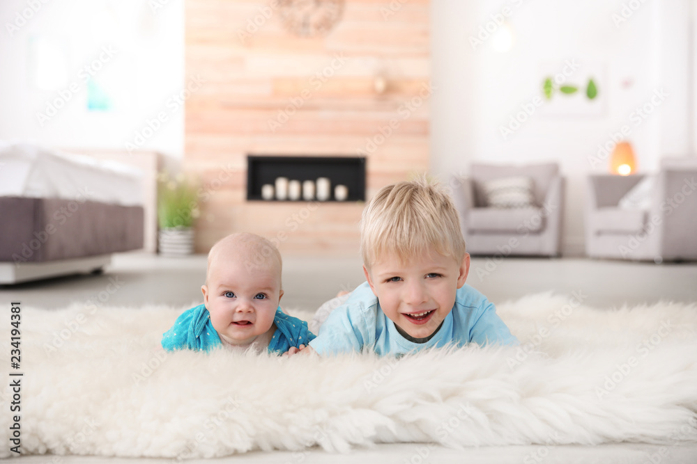 Cute boy with his little sister lying on fur rug at home Cute boy with his little sister lying on fur rug at home