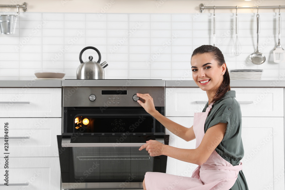 Young woman baking something in oven at home Young woman baking something in oven at home