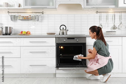 Young woman baking something in oven at home