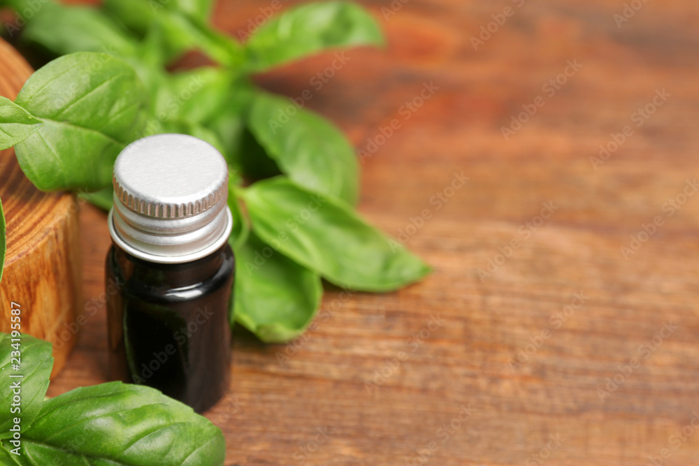 Glass bottle of basil oil with leaves and space for text on wooden table Glass bottle of basil oil with leaves and space for text on wooden table