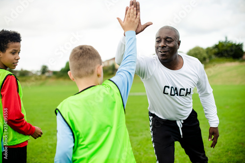 Tela Football coach doing a high five with his student