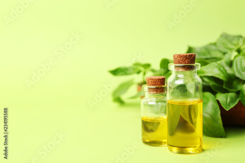 Bottles of basil oil and leaves with space for text on color background