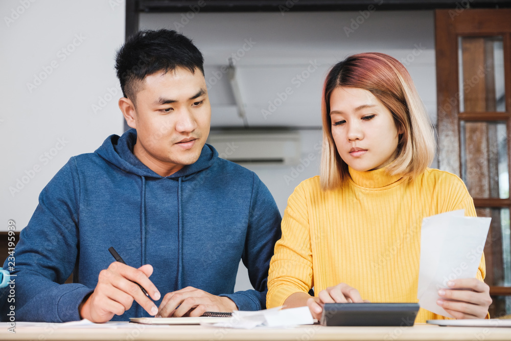 Asian couple list home financial bill budget on table in kitchen at new house. Asian couple list home financial bill budget on table in kitchen at new house.
