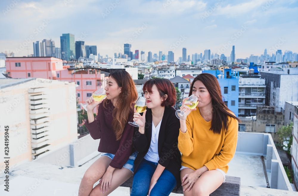 Fototapeta premium Happy group of asian girl friends enjoy laughing and cheerful sparkling wine glass at rooftop party,Holiday celebration festive,teeage lifestyle,freedom and fun.