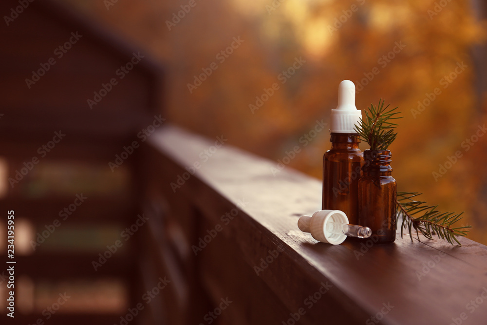 Glass bottles with essential oil and ingredient on blurred background. Space for text