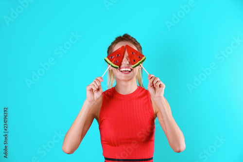 Young pretty woman with candies on colorful background