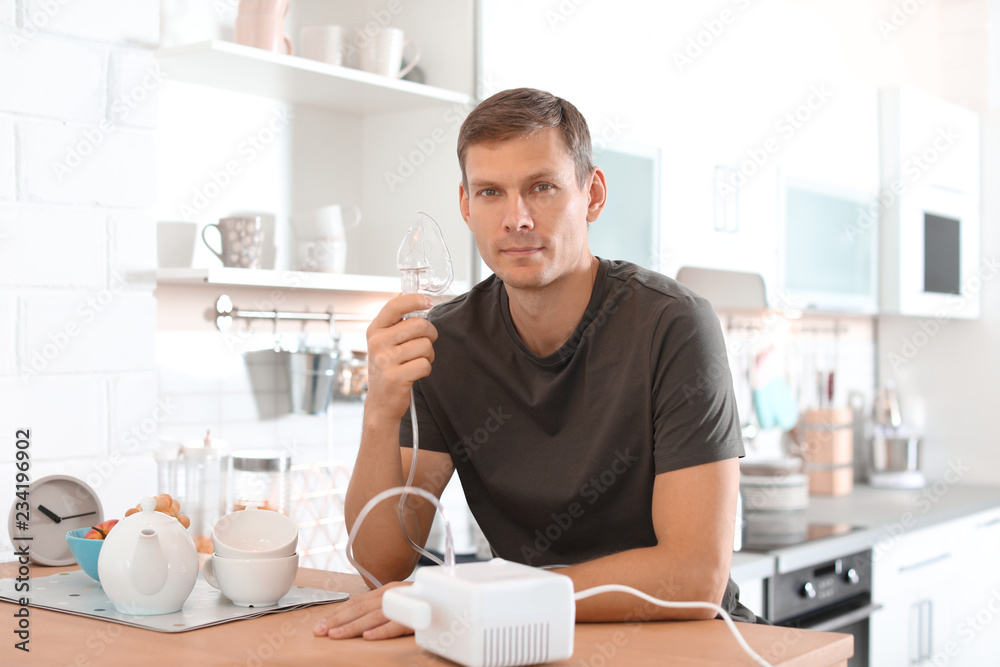 Man using asthma machine at table in kitchen Man using asthma machine at table in kitchen