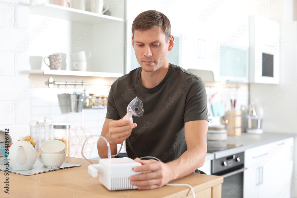 Man using asthma machine at table in kitchen Man using asthma machine at table in kitchen