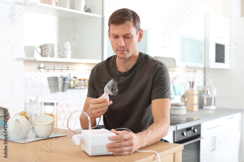 Man using asthma machine at table in kitchen
