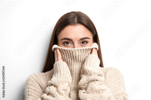 Beautiful young woman in warm sweater on white background