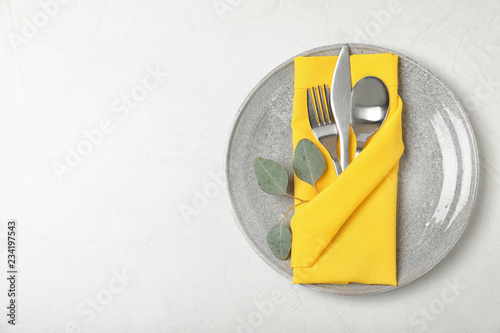 Plate with cutlery and napkin on light background, top view. Space for text