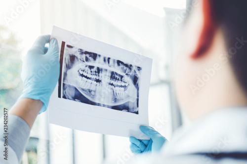 Dentist consulting with patient presenting results on Dental x-ray film About the problem of the patient photo