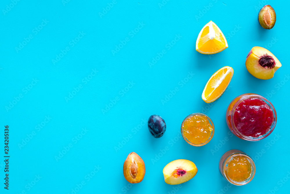 Jams different tastes made of fruits and berries near pieces of fruits on blue background top view copy space
