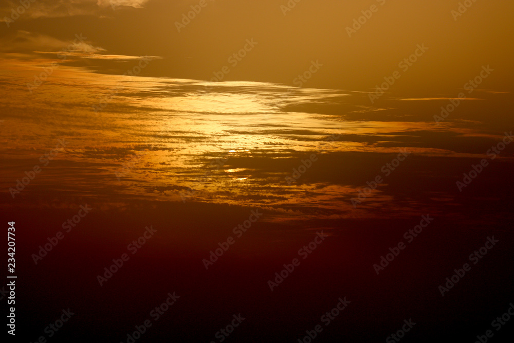 sunset at sea, red sun sits behind the horizon