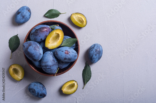 Fresh plums in bowl on wooden table