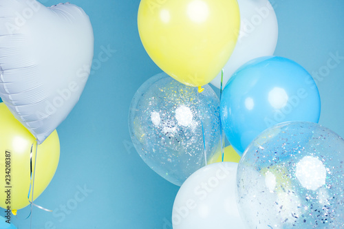 yellow, blue and white balloons on blue wall background copy space. Colorful balloon in room prepared for birthday party. copyspace helium balloons
