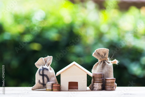 US dollar in a money bag, small residential, house model on table.